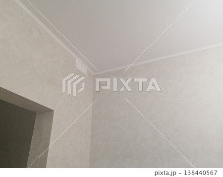 Clean interior corner featuring textured beige wallpaper, white ceiling molding, and neutral tones Clean interior corner featuring textured beige wallpaper, white ceiling molding, and neutral tones 138440567