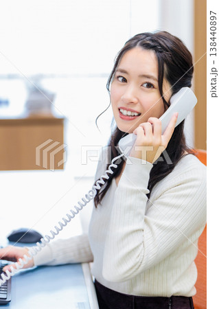 パソコンを見ながら電話を受ける女性 パソコンを見ながら電話を受ける女性 138440897