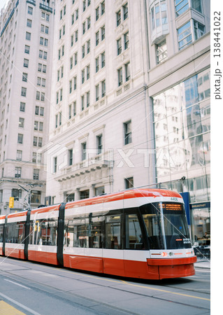 Red Tram Travels Swiftly Through Bustling Downtown Streets In Morning Red Tram Travels Swiftly Through Bustling Downtown Streets In Morning 138441022