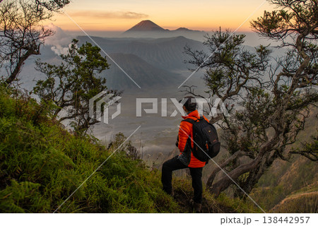 Rear view of tourist standing on the hill and looking to the beautiful sunrise of Bromo Tengger Semeru National Park in East Java, Indonesia. Rear view of tourist standing on the hill and looking to the beautiful sunrise of Bromo Tengger Semeru National Park in East Java, Indonesia. 138442957