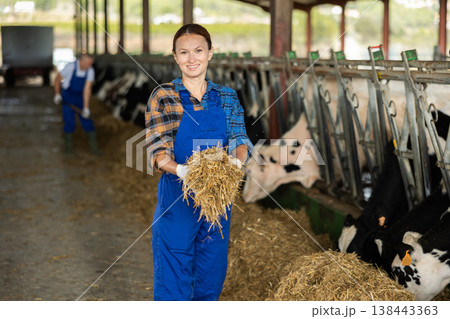 Adult woman feeding cows hay on farm 138443363