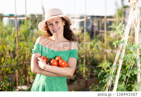 Adult woman posing with tomatoes in garden 138443387