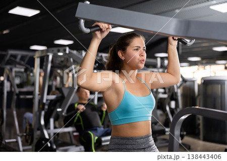 Young girl working out on lat pulldown lever machine Young girl working out on lat pulldown lever machine 138443406