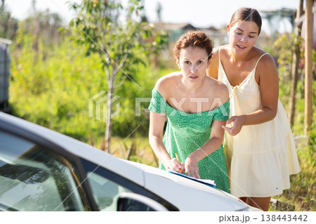 Adult and young woman signing document on car 138443442