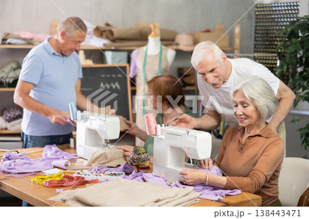Some people communicate and discuss pattern, while others sew using sewing machine at lesson Some people communicate and discuss pattern, while others sew using sewing machine at lesson 138443471
