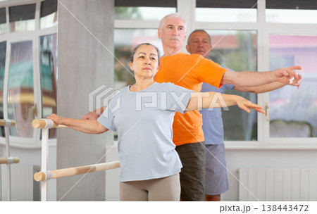 Close-up view of mature woman practicing ballet positions standing by ballet-barre 138443472
