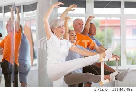 Ballet pose grand batman - elderly women and men at choreography lesson Ballet pose grand batman - elderly women and men at choreography lesson 138443488