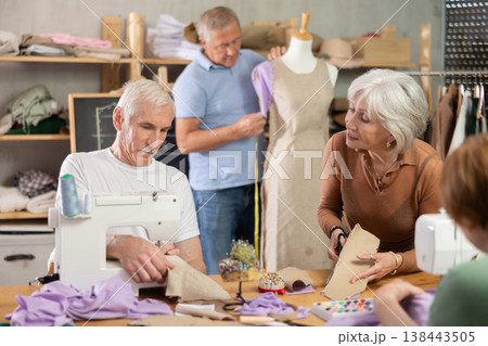Some people talking, while others sew, work with mannequin, cut out dress pattern 138443505