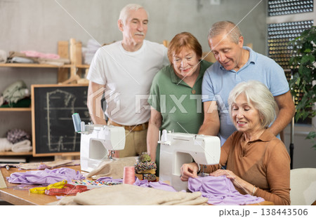 Seamstress explaining sewing techniques to older adults in training workshop Seamstress explaining sewing techniques to older adults in training workshop 138443506