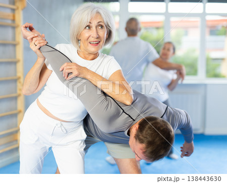 Mature woman learns how to do painful hold with trainer in gym. Self-defense lesson 138443630
