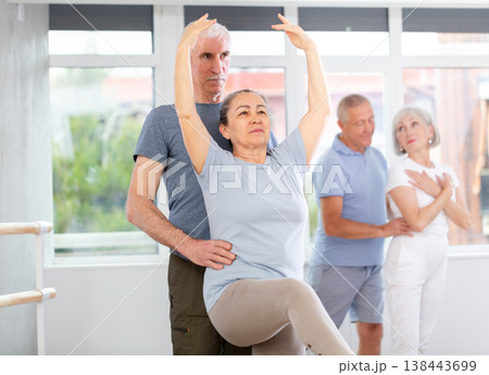 Mature woman practicing ballet positions in pair with man in dance studio 138443699