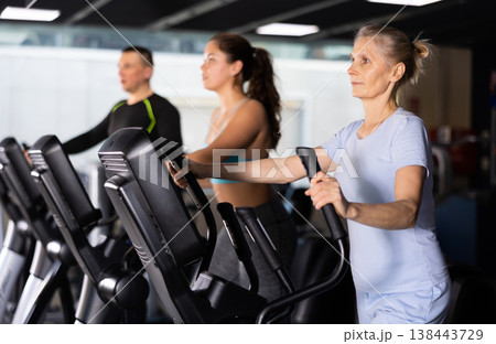 Mature female athlete working out at elliptical machine in gym 138443729