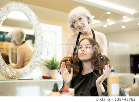 Professional hairdresser is doing fashionable haircut to young woman in hairdress salon 138443762