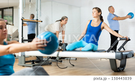 Woman performing pilates exercises on reformer in fitness studio 138443839