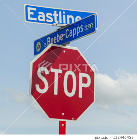 Red octagonal stop sign mounted beneath blue street signs at an intersection against a bright blue sky with fluffy clouds, conveying traffic control, safety, direction and urban signage Red octagonal stop sign mounted beneath blue street signs at an intersection against a bright blue sky with fluffy clouds, conveying traffic control, safety, direction and urban signage 138446458
