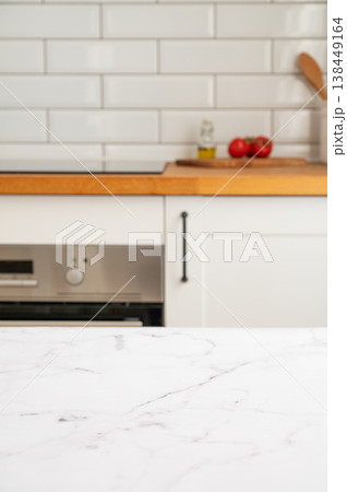 Modern marble kitchen countertop with oven, cooktop and white tiles in the background Modern marble kitchen countertop with oven, cooktop and white tiles in the background 138449164