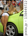 Attractive promo girl in white shorts posing on a lime green car at a car show 138449722