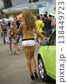 Attractive promo girl in white shorts posing on a lime green car at a car show 138449723