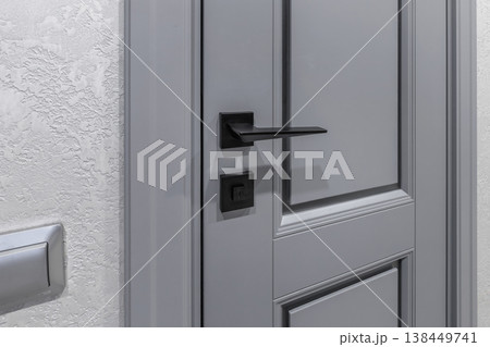 Black Minimalist Door Handle on Classic Grey Door Panel 138449741