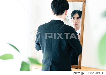鏡の前で身だしなみを整えるスーツ姿の男性 138450931