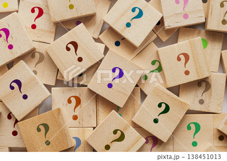 Too many wooden cubes with colorful question marks. Scattered blocks on blurred background symbolize curiosity and problem solving 138451013