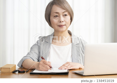 契約書に署名捺印するシニア女性 138451019