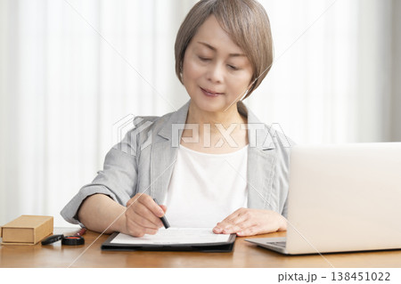 契約書に署名捺印するシニア女性 138451022