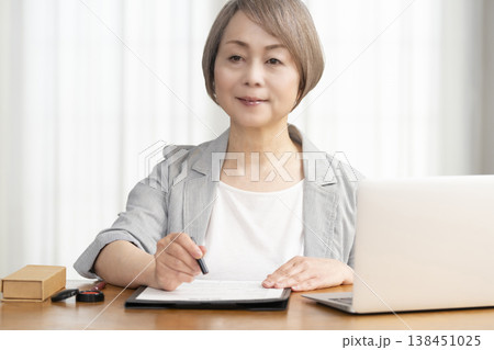 契約書に署名捺印するシニア女性 138451025