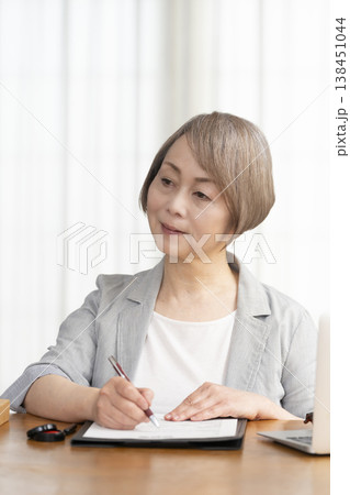 契約書に署名捺印するシニア女性 138451044