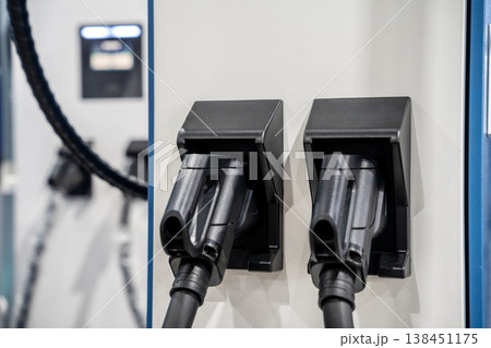 Electric car charging on parking lot with electric car charging station on city street. Close up of power supply plugged into an electric car being charged. 138451175