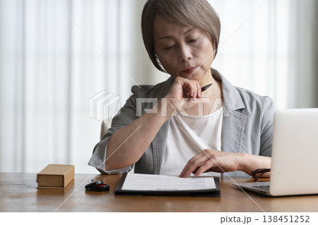 契約書に署名捺印を悩むシニア女性 ネガティブ 契約書に署名捺印を悩むシニア女性 ネガティブ 138451252