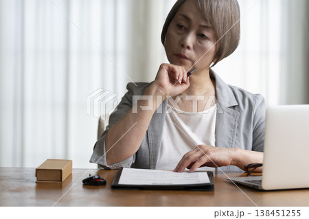 契約書に署名捺印を悩むシニア女性　ネガティブ 138451255