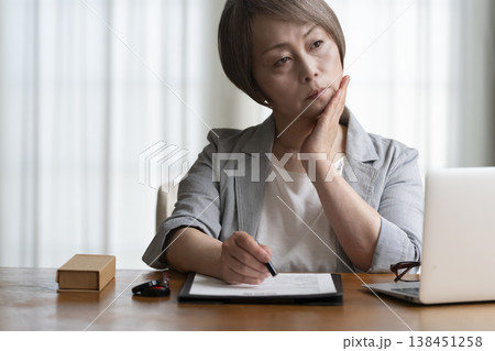 契約書に署名捺印を悩むシニア女性　ネガティブ 138451258