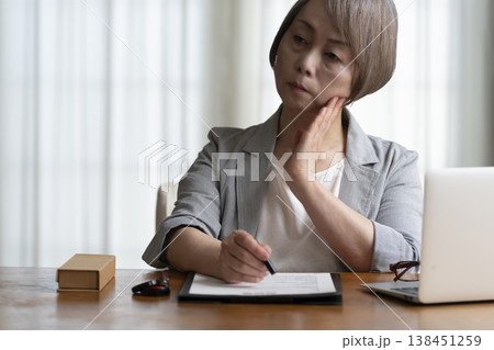 契約書に署名捺印を悩むシニア女性 ネガティブ 契約書に署名捺印を悩むシニア女性 ネガティブ 138451259