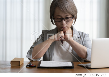 契約書に署名捺印を悩むシニア女性 ネガティブ 契約書に署名捺印を悩むシニア女性 ネガティブ 138451266