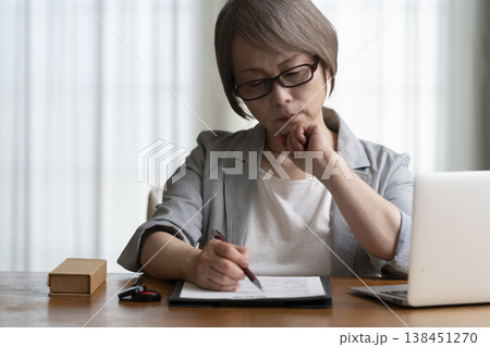 契約書に署名捺印を悩むシニア女性　ネガティブ 138451270