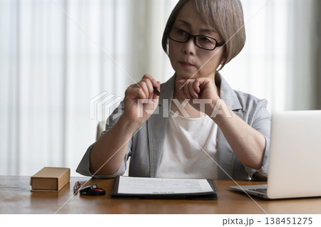 契約書に署名捺印を悩むシニア女性 ネガティブ 契約書に署名捺印を悩むシニア女性 ネガティブ 138451275