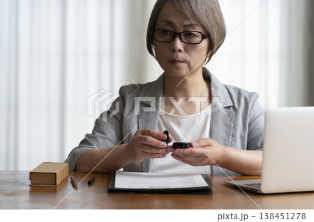 契約書に署名捺印を悩むシニア女性 ネガティブ 契約書に署名捺印を悩むシニア女性 ネガティブ 138451278