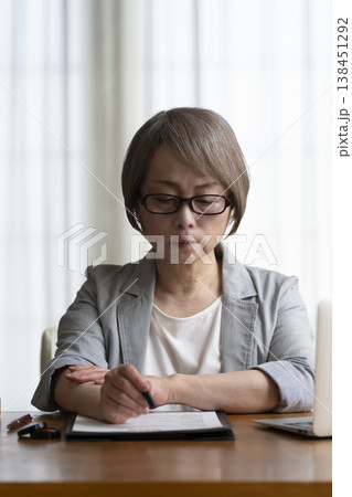 契約書に署名捺印を悩むシニア女性 ネガティブ 契約書に署名捺印を悩むシニア女性 ネガティブ 138451292