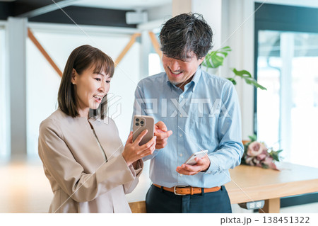 オフィスでスマホを見るビジネスウーマンとビジネスマン（IT企業・会社員） 138451322