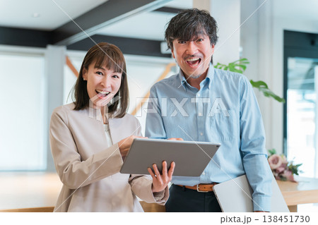タブレットを見て喜ぶビジネスウーマンとビジネスマン（業績アップ,黒字,成績,成功,売上アップ） 138451730