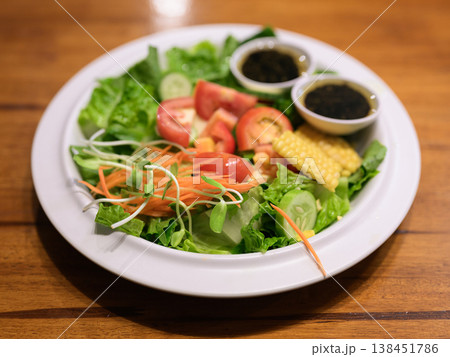 Fresh Mixed Garden Salad with Dressing on Wooden Table and Copy Space Fresh Mixed Garden Salad with Dressing on Wooden Table and Copy Space 138451786