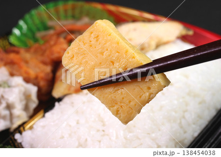 パック弁当から玉子焼きを箸で持ち上げる風景 138454038