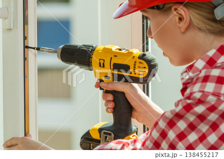 Woman using drill on window Woman using drill on window 138455217