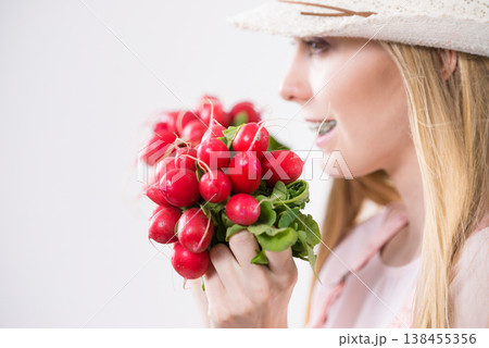 woman holding radish close to face woman holding radish close to face 138455356