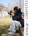ベンチに座って桜を見ている女の子 138455753
