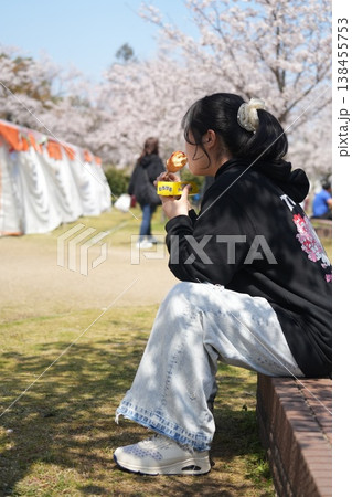 ベンチに座って桜を見ている女の子 138455753