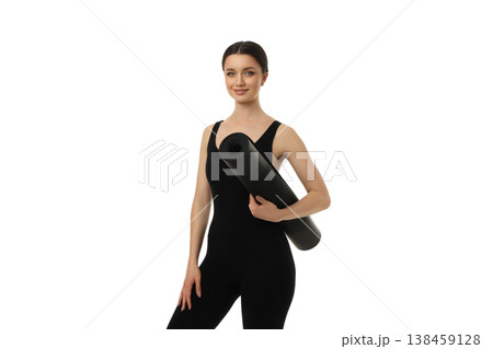Yoga woman holds a black mat while standing in studio, PNG 138459128