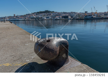 Close-up of a cast iron mooring bollard in the port of Vigo with the city and shipyards in the background. 138459291