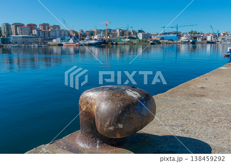Close-up of a cast iron mooring bollard in the port of Vigo with the city and shipyards in the background. 138459292